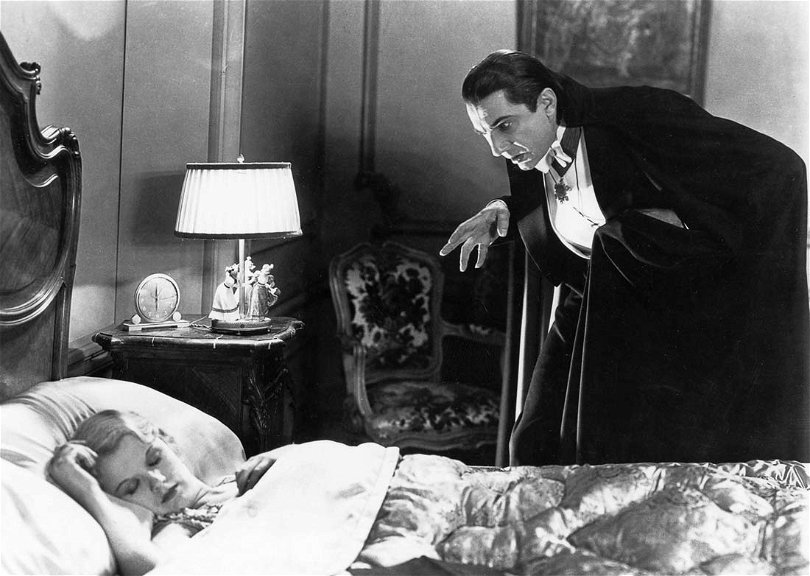 Bela Lugosi står som Dracula lutande över en kvinna som sover.