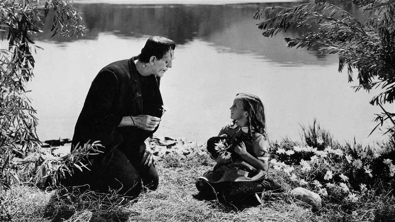 Ur Frankenstein. Monstret och en liten flicka sitter i gräset och plockar blommor vid en sjö.