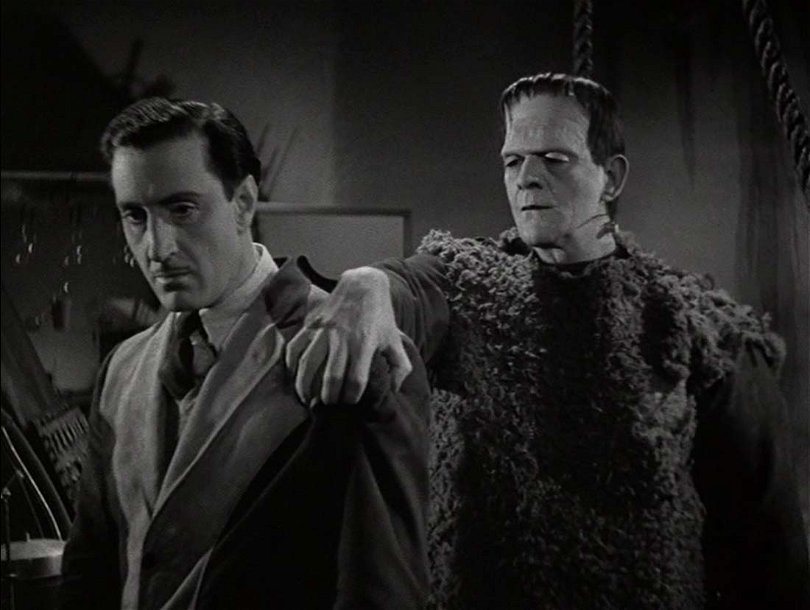 Ur Frankensteins son. Monstret till höger står bakom Frankenstein och håller en hand på hans axel. 