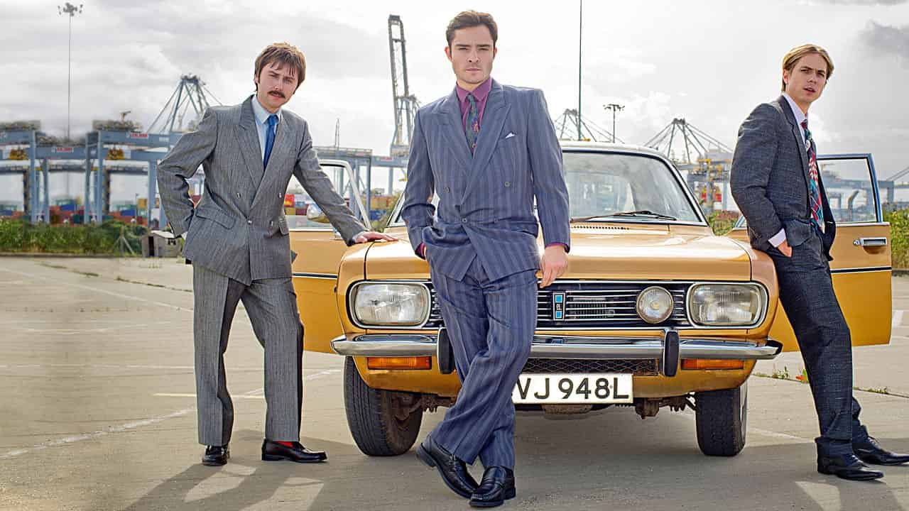 Vincent (Westwick), Brian (Buckley) och Lavender (Thomas) från White Gold står lutade mot en gul bil.