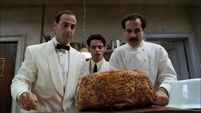Från filmen Big Night. Tre personer står i ett kök och stirrar på en enorm stek. 