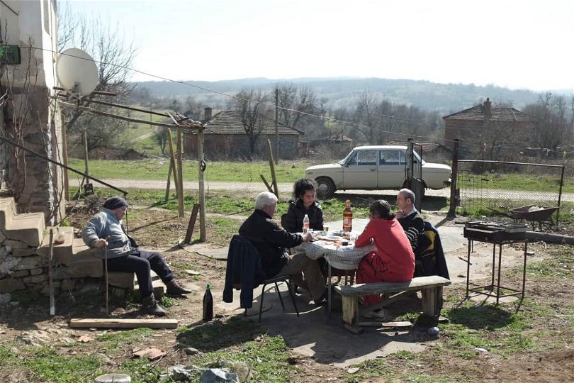 Från filmen "The Good Postman" i regi av Tonislav Hristov. På bilden syns fyra personer sitta utomhus vid ett bord. 