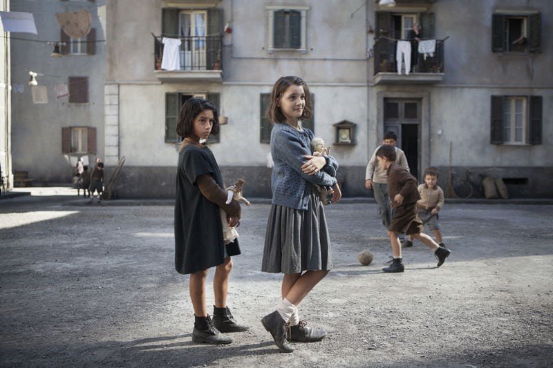Två flickor står på en bakgård i Neapel.