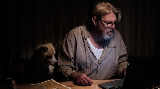 Rolf Lassgård och en hund betraktar en dator i ett mörkt rum