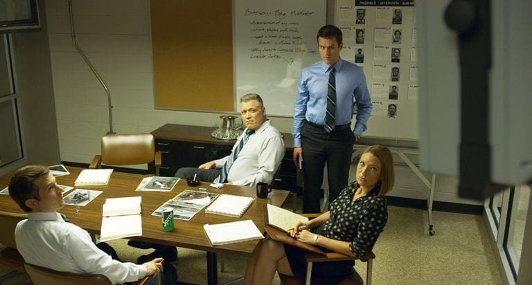 Bild från David Finchers Netflix-serie Mindhunter. Karaktärerna Holden Ford, Bill Tench och Dr. Wendy Carr syns i bild, arbetandes på sitt kontor. 
