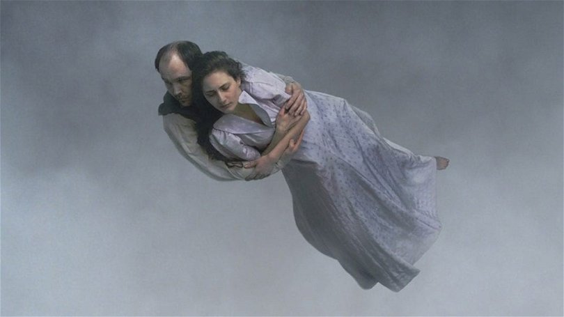 En man och en kvinna svävar fram genom molnen i Roy Anderssons "Om det oändliga".