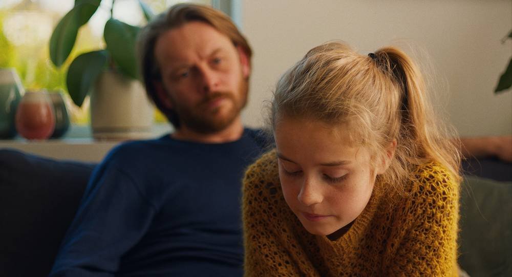 Bild från den norska filmen Barn föreställandes flickan Lykke i förgrunden och läraren Anders i bakgrunden. 