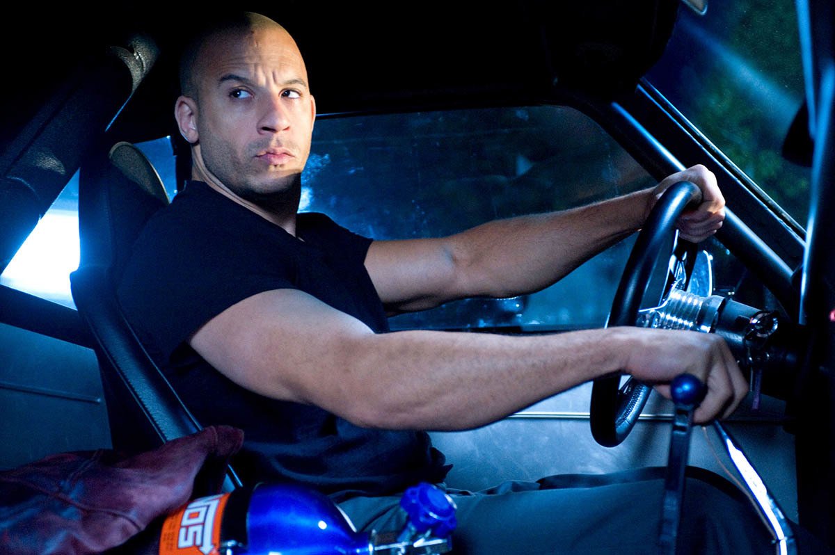Dominic Toretto (Vin Diesel) spänner musklerna bakom ratten på en muskelbil. Foto: Universal Pictures.