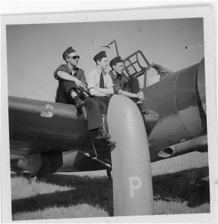 Svartvit bild på en ung Anders Rogberg och ett par andra piloter som sitter på vingen på ett stridsflygplan. Foto: Lightray Productions. 
