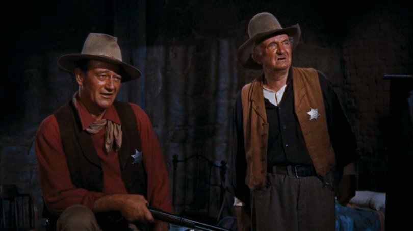 John Wayne och Walter Brennan står bredvid varandra i västernkläder.