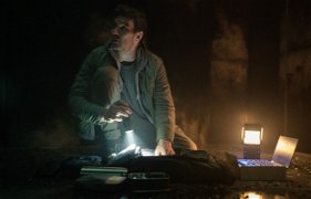 Jason sitter vid sin tekniska utrustning i ett mörkt rum 